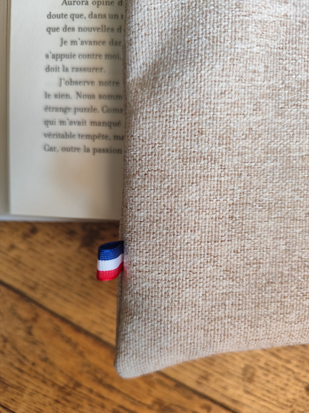 Housse livre en lin naturel avec fermeture bouton écaille, posée sur un livre ouvert